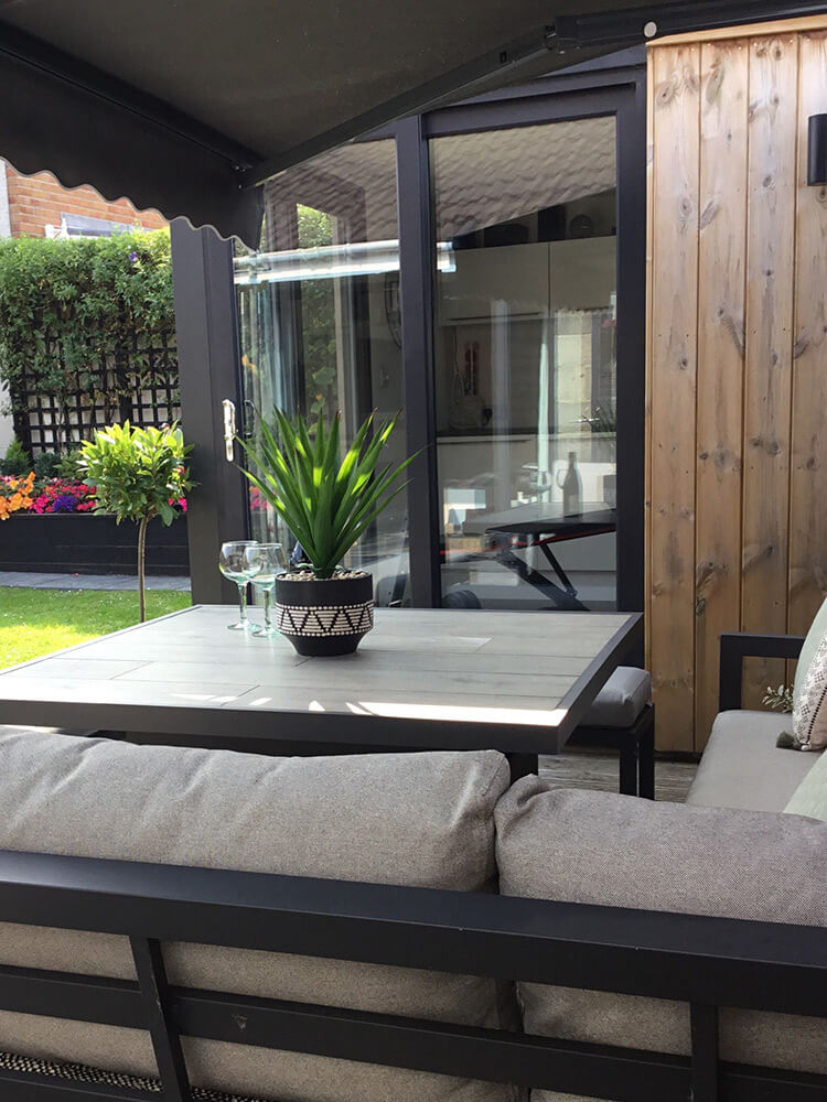 exterior of completed custom garden studio. includes outdoor furniture and potted greenery.